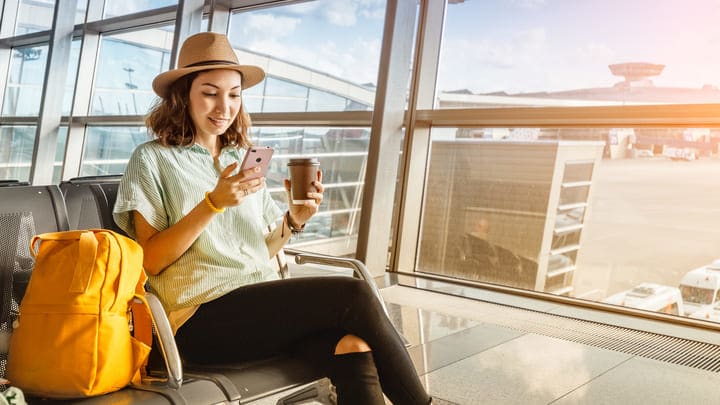 Woman having a coffee and checking her phone in the airport