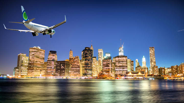 Aeroplane descending over the brightly illuminated Manhattan skyline at night